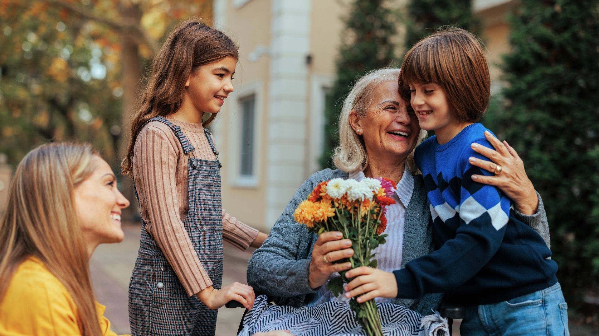 Senior woman hugging grandchildren with flowers