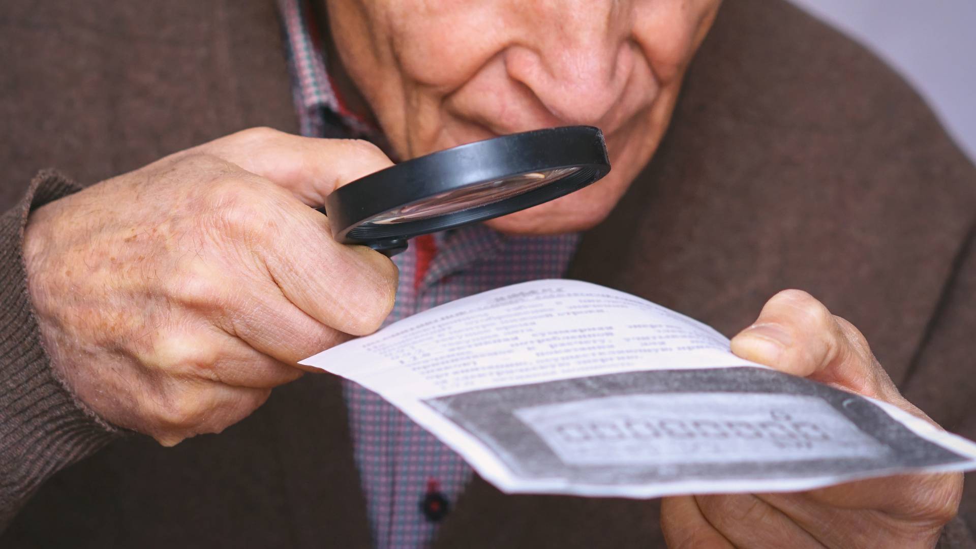 Senior man using magnifying glass to read paper