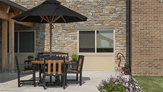 Table with umbrella and chairs sitting on patio in the backyard of Boonespring Transitional Care Center and Rehabilitation in Boone Co., KY