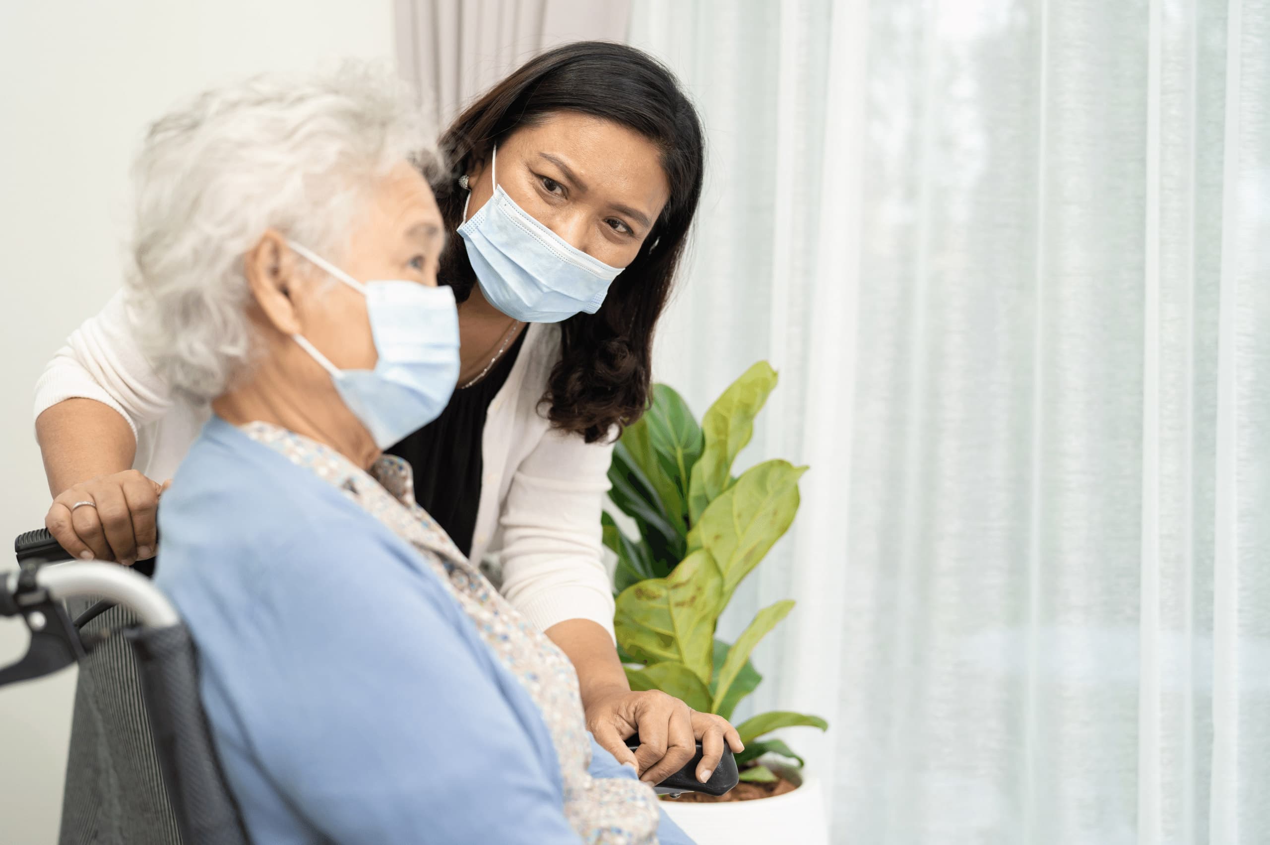 senior woman and caregiver wearing masks