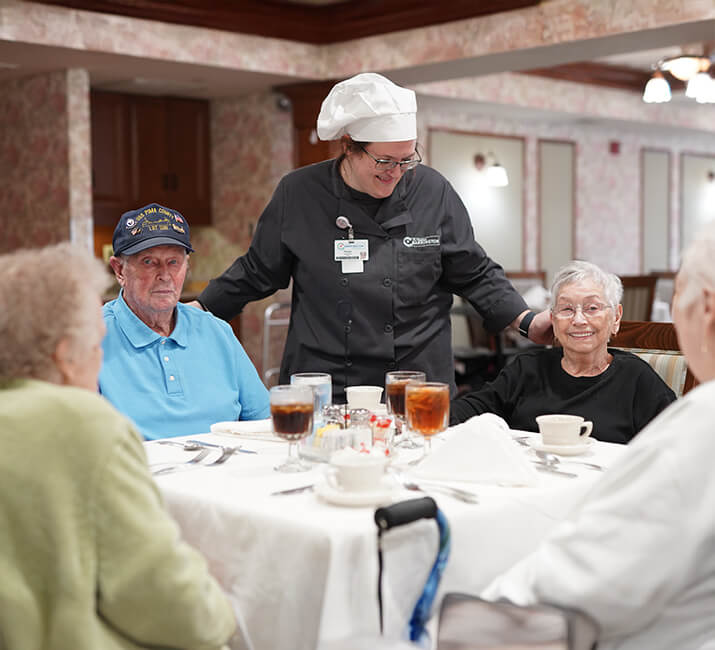chef checking in on a table of dining seniors