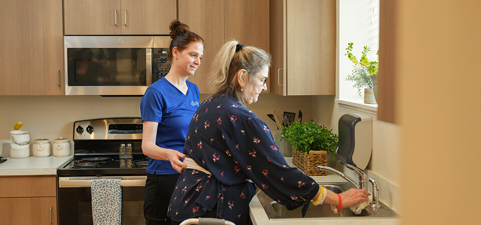 employee helping senior woman clean her kitchen