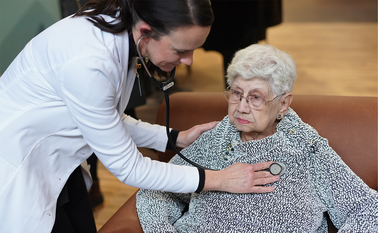 Healthcare professional checking the heart rate of an elderly woman.