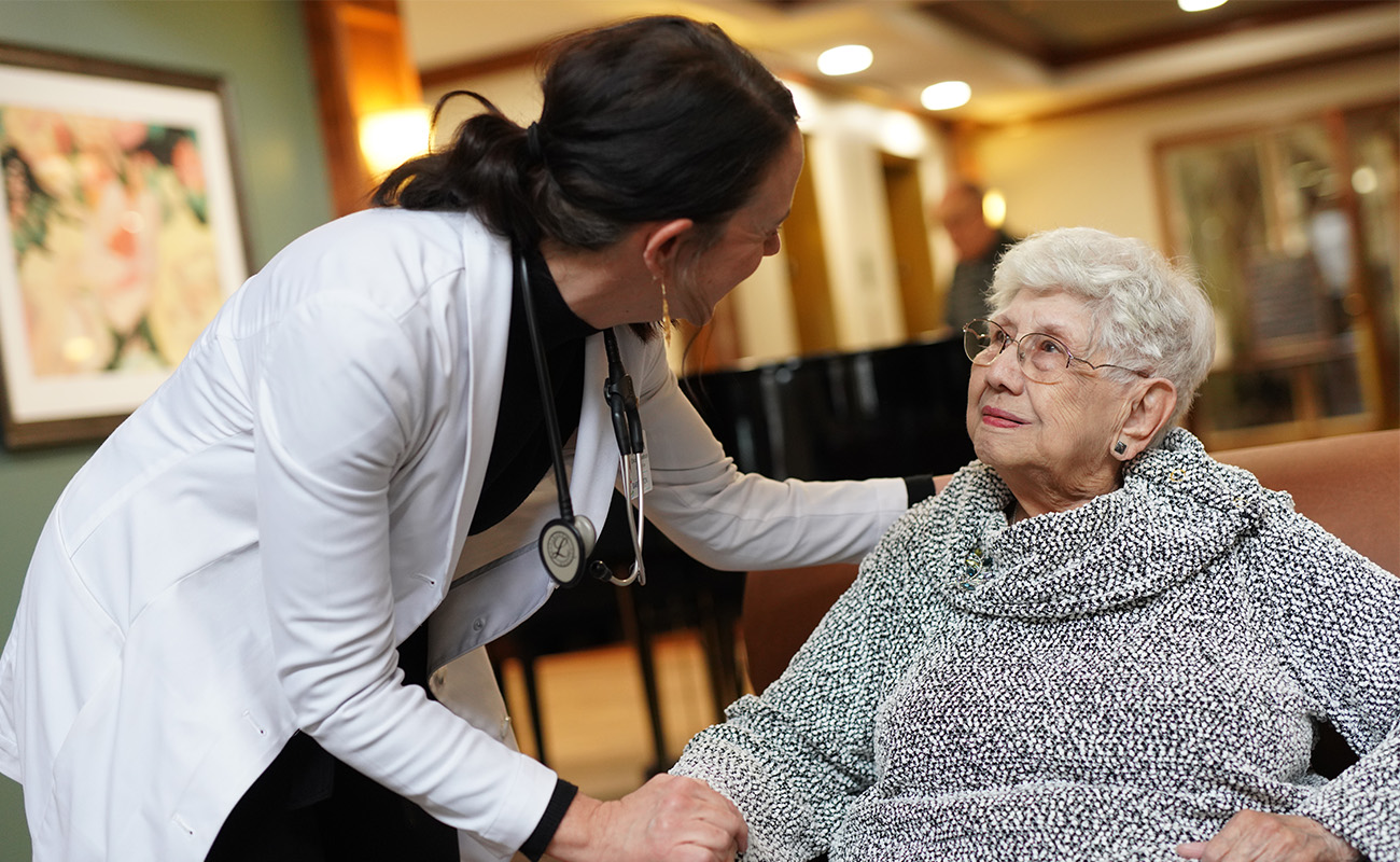 Nurse interacting with elderly woman in a community common area.