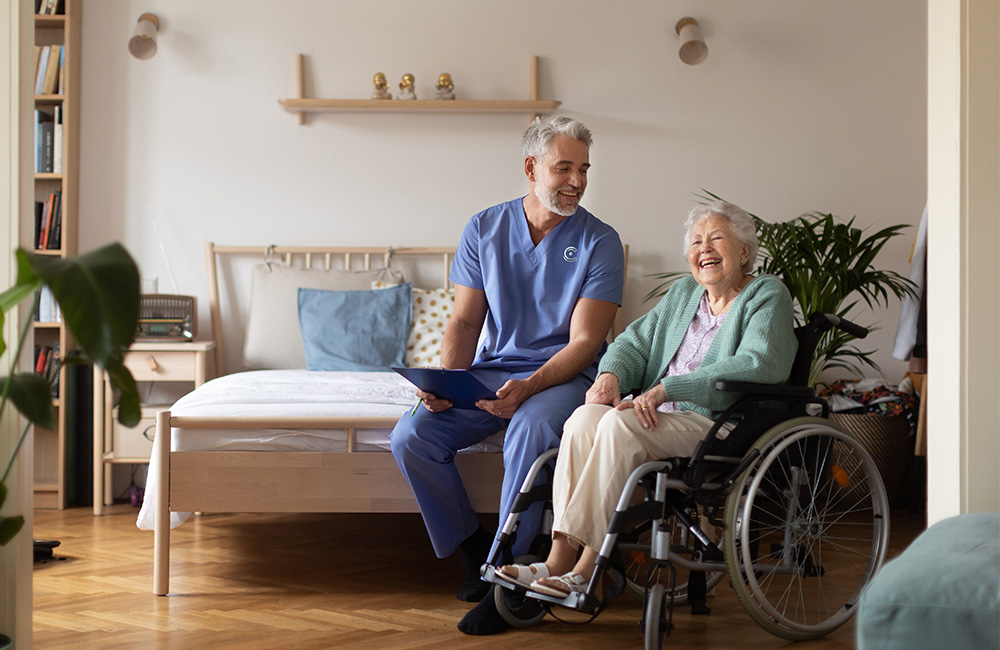 Caregiver with elderly woman in a wheelchair sharing a joyful moment in a cozy living space.