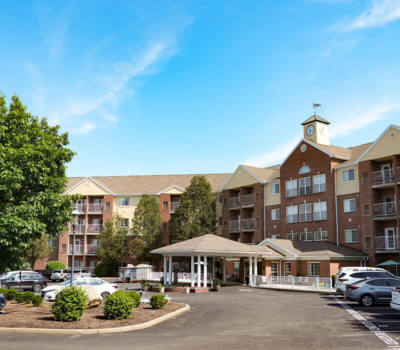 Brick senior living building with multiple units and a clock tower.