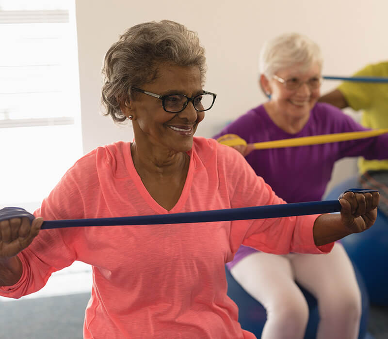 Elderly women exercising with resistance bands in a community fitness class.