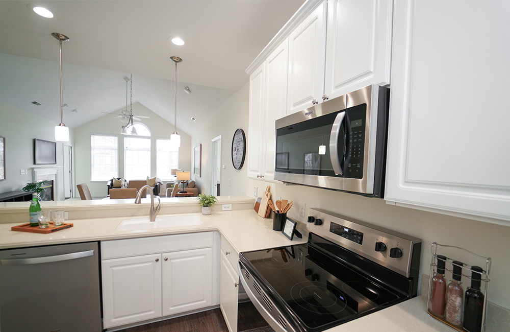 Modern kitchen in a unit with stainless steel appliances and white cabinets.