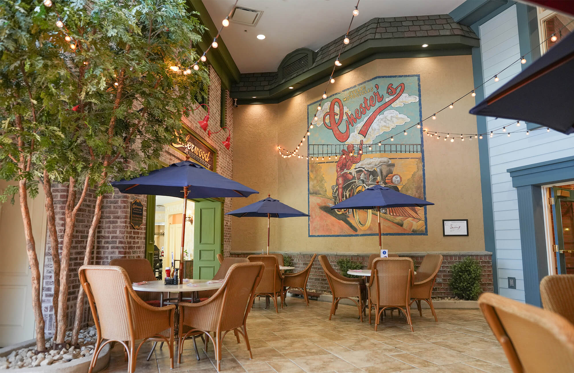 Charming courtyard with tables, string lights, and mural in a residential community.