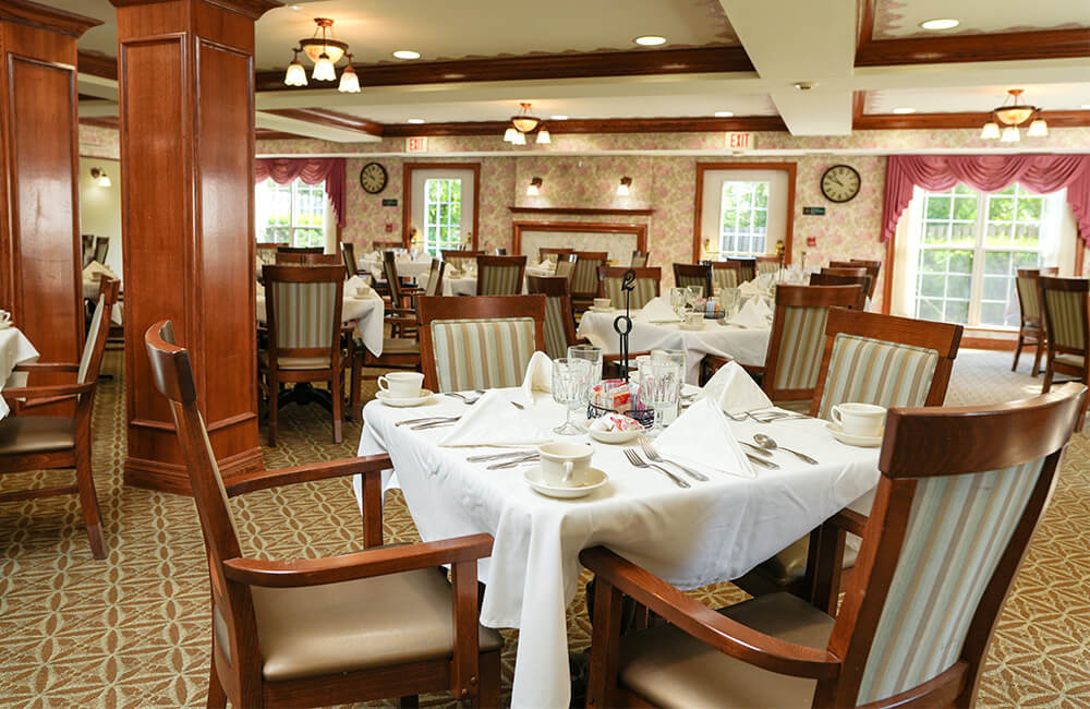 Elegant dining room with set tables and wooden chairs in a residential community.