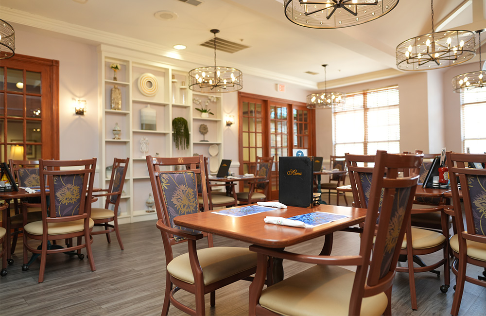 Elegant dining room with wooden tables and chairs in a senior living community.