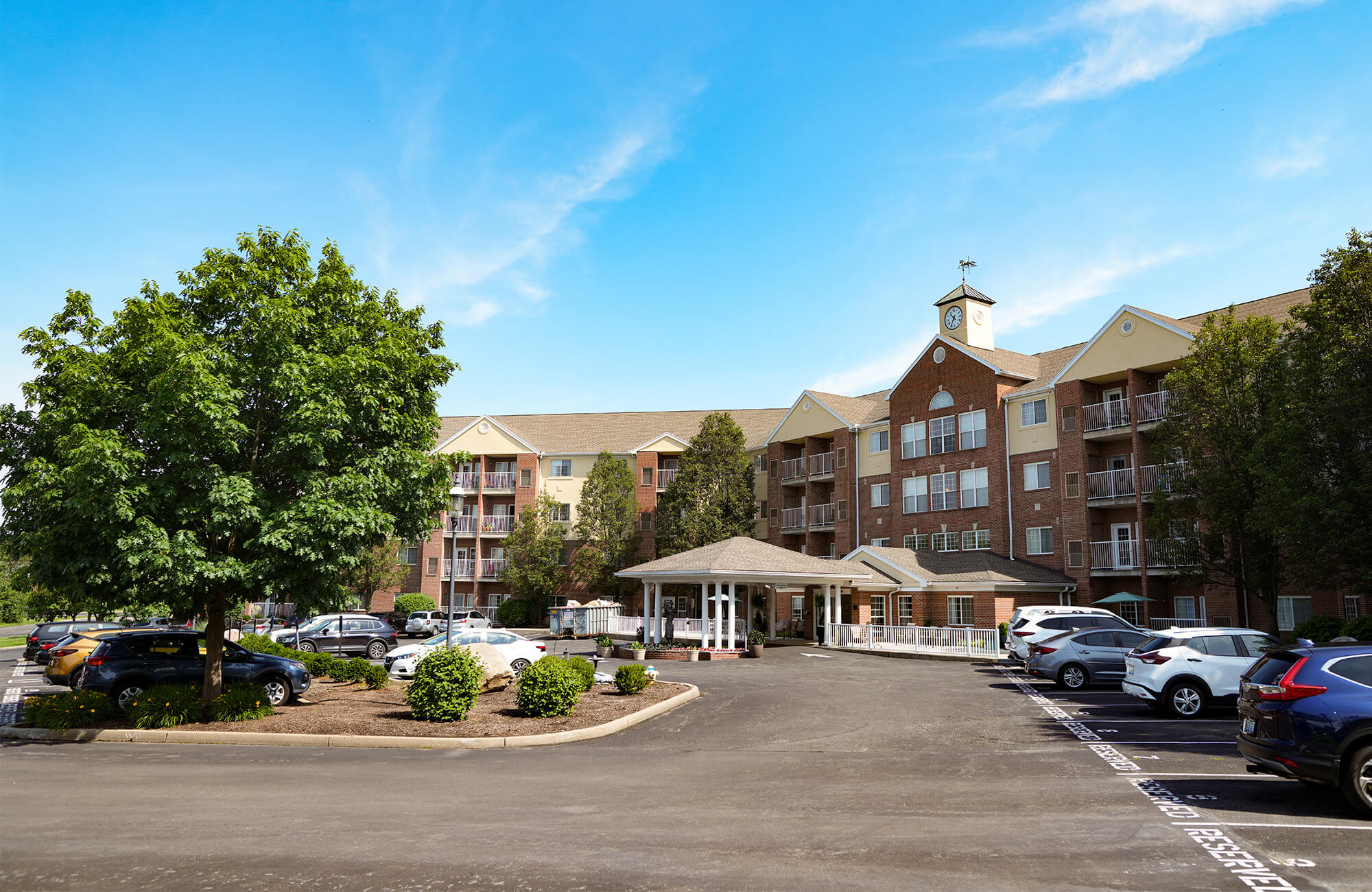 A large brick building with balconies and a clock tower under a clear blue sky.