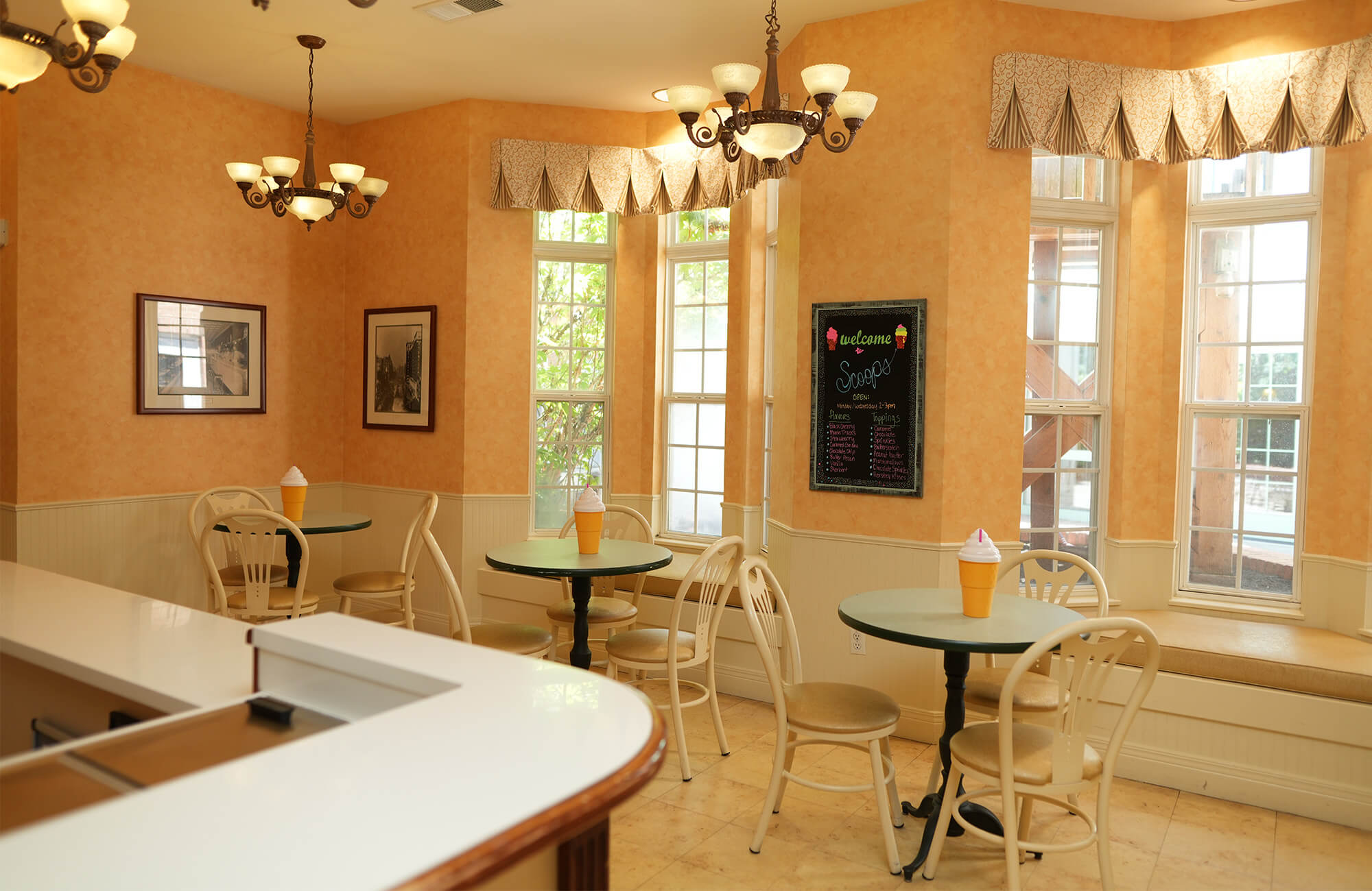 Cozy dining area with round tables in a warm-colored senior community common room.