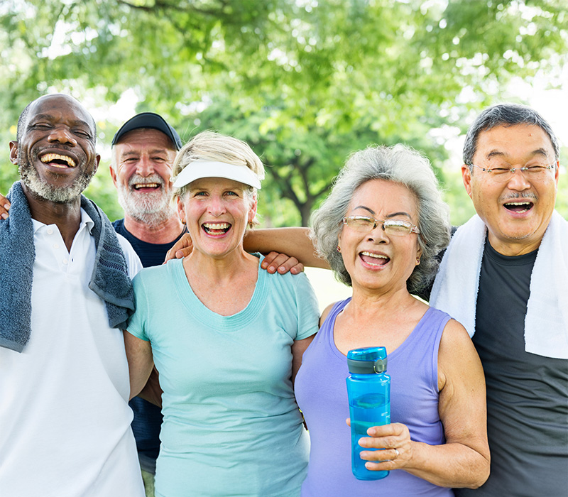 Group of seniors laughing together outdoors during a sunny day at the park.