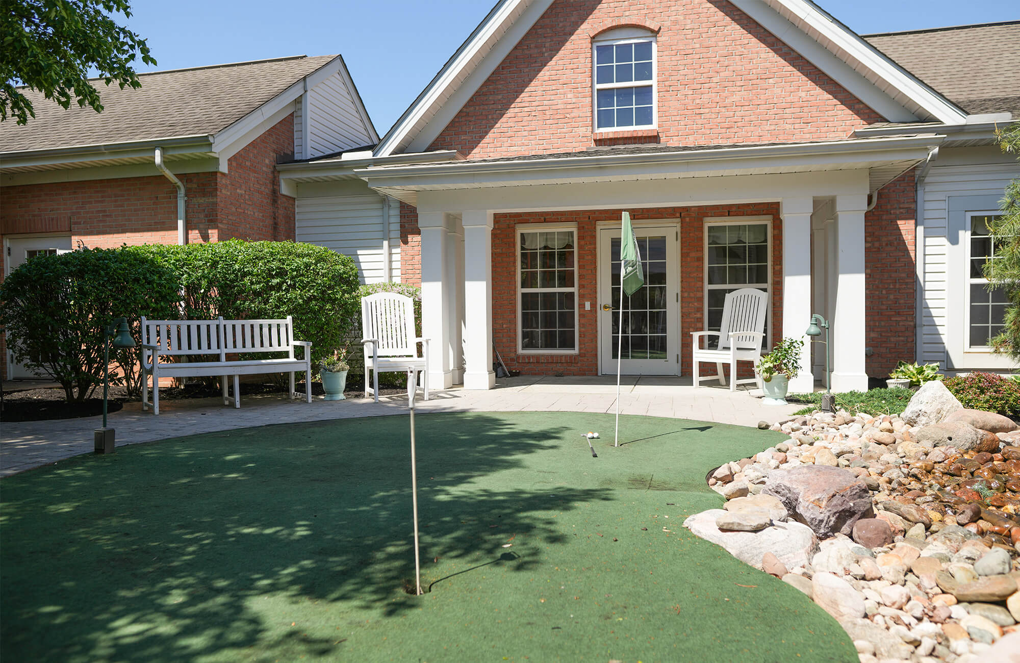 Exterior view of main residential building with putting green and benches.