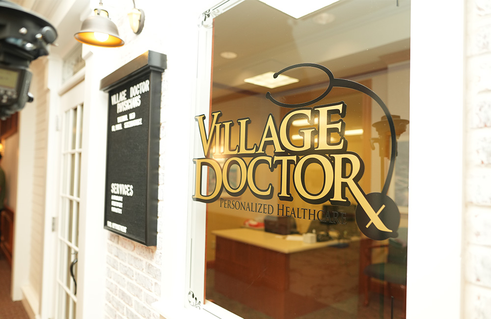 Medical office signage with glass door reflecting indoor space.