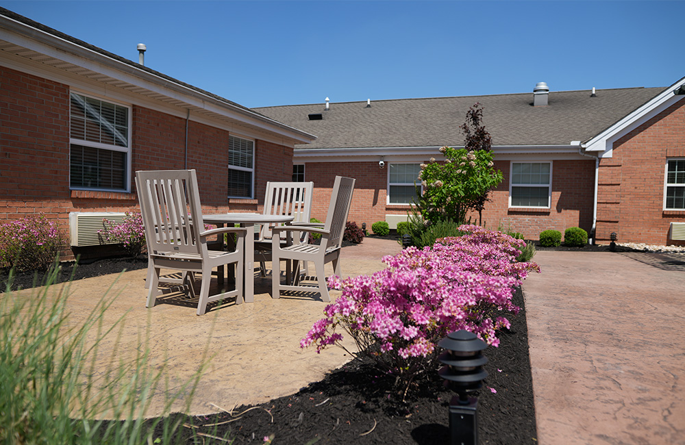Outdoor patio with chairs and blooming flowers in a senior community setting.