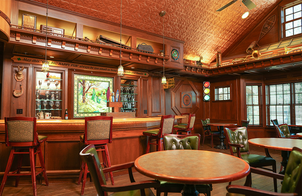 Warm, inviting pub-style space with wooden bar and colorful stained glass in senior community.