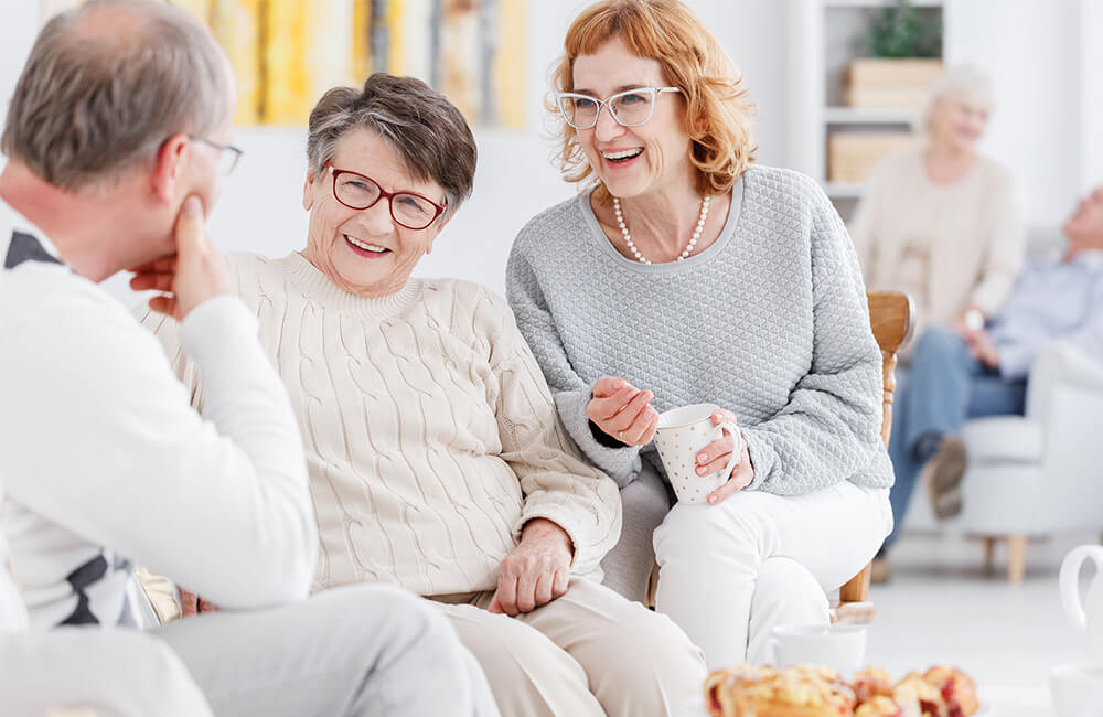 Residents enjoying social time in a brightly lit common area of a senior living community.
