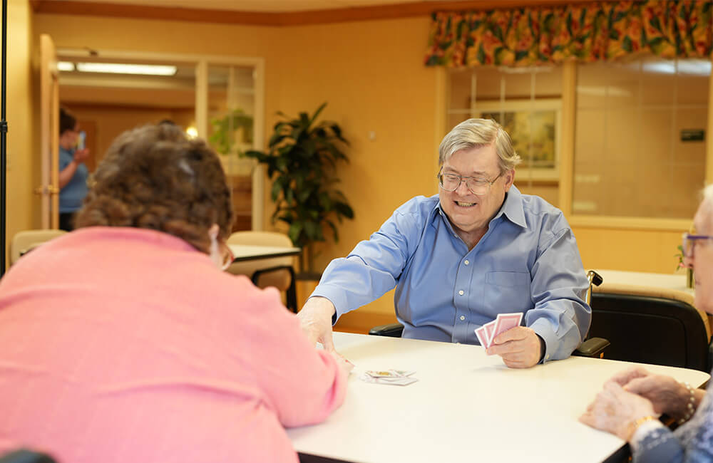 Residents enjoy a lively card game in a social area within the community building.