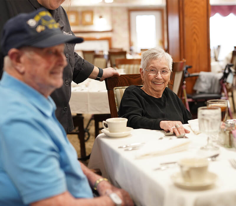 Seniors enjoying a meal in the dining area of a senior living community.