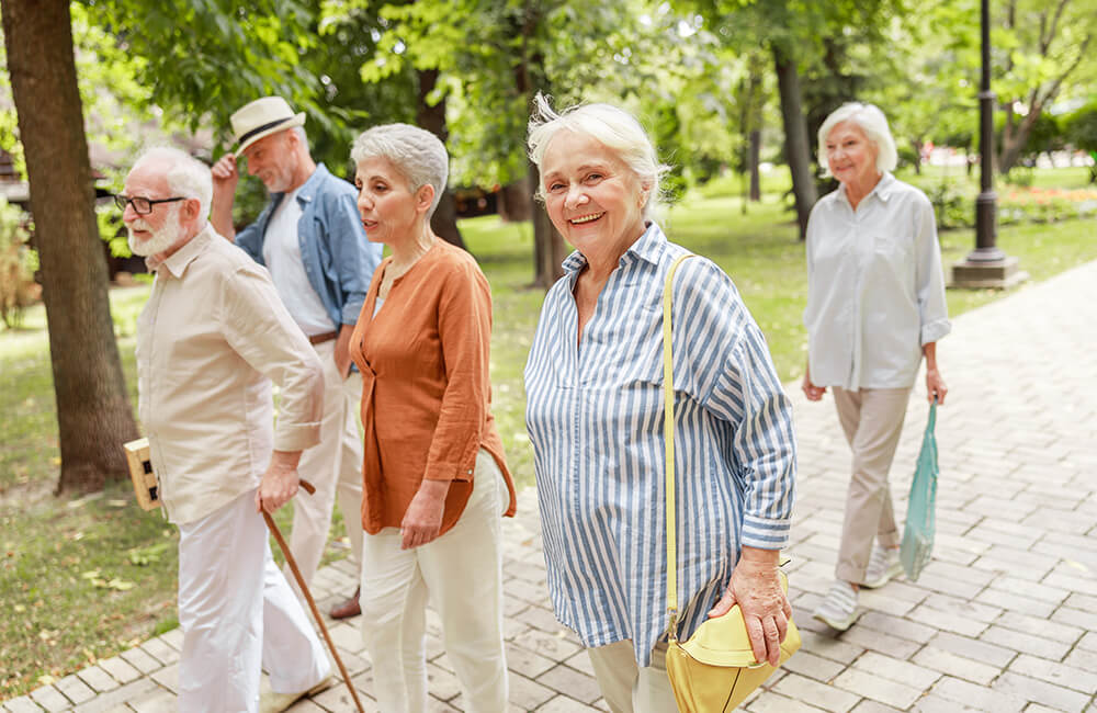 Seniors walking together in a lush park, enjoying a sunny day.