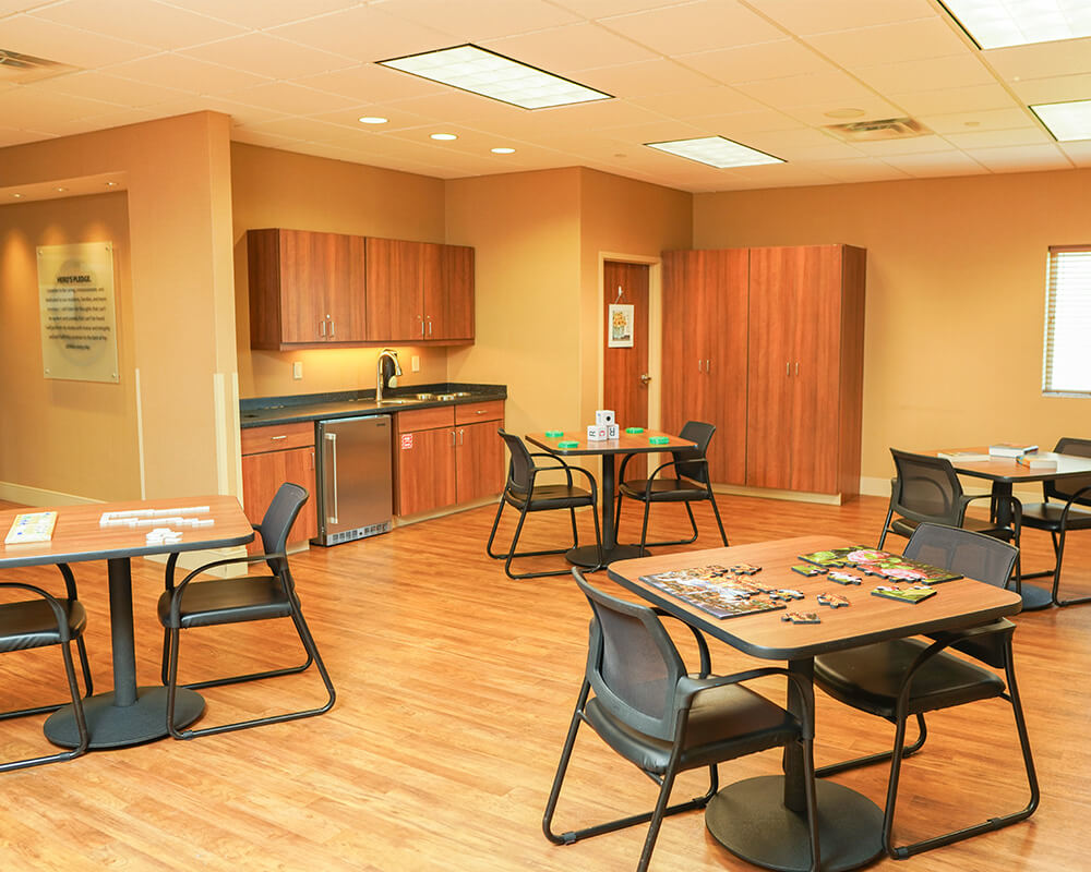 Bright activity room with tables and chairs in a senior community.