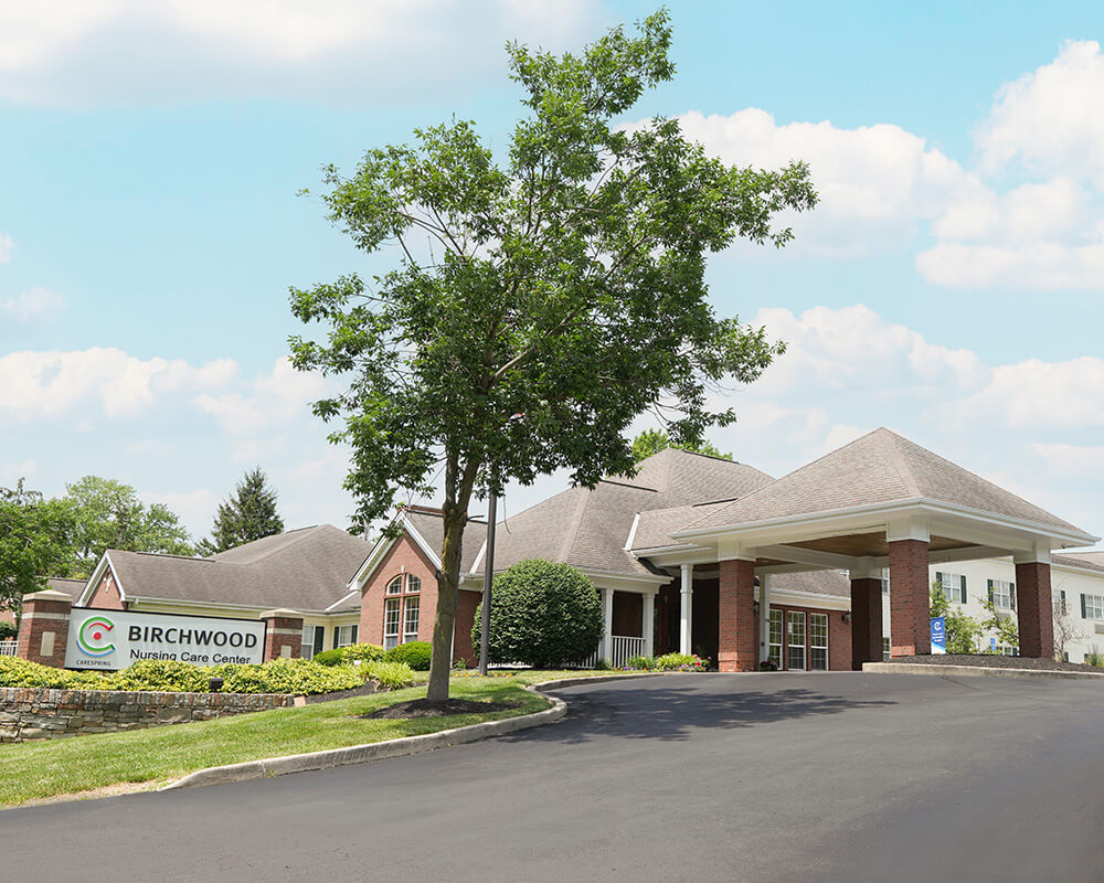 Entrance of a senior living community with signage and landscaped surroundings.