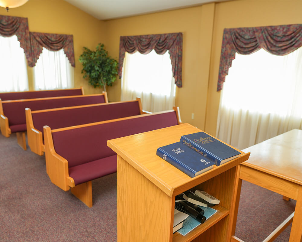 Chapel area with wooden pews and books on a podium in a senior living community.