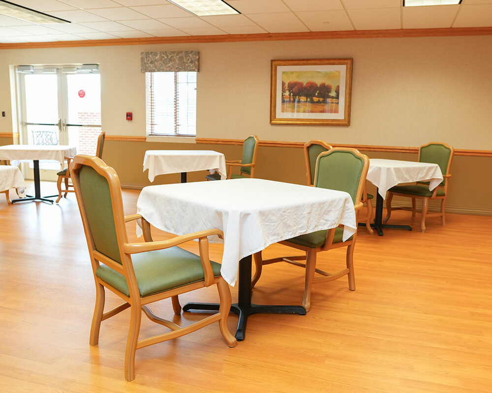Dining area with tables and chairs in a communal space for residents.