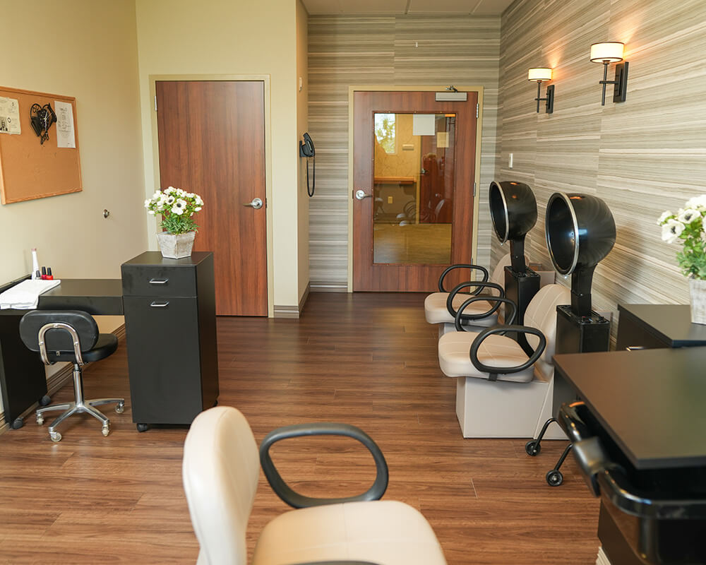 Hair salon with drying stations and stylist chair in a senior community building.