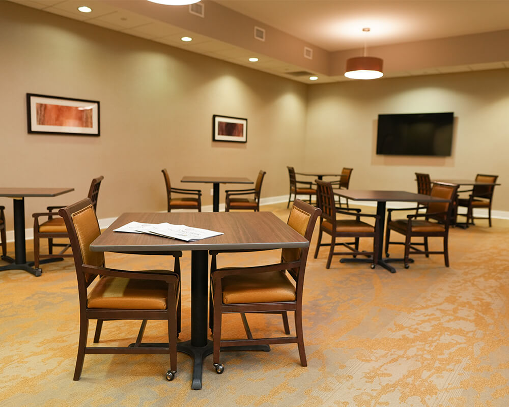 Spacious seating area with tables, chairs, wall art, and a television.