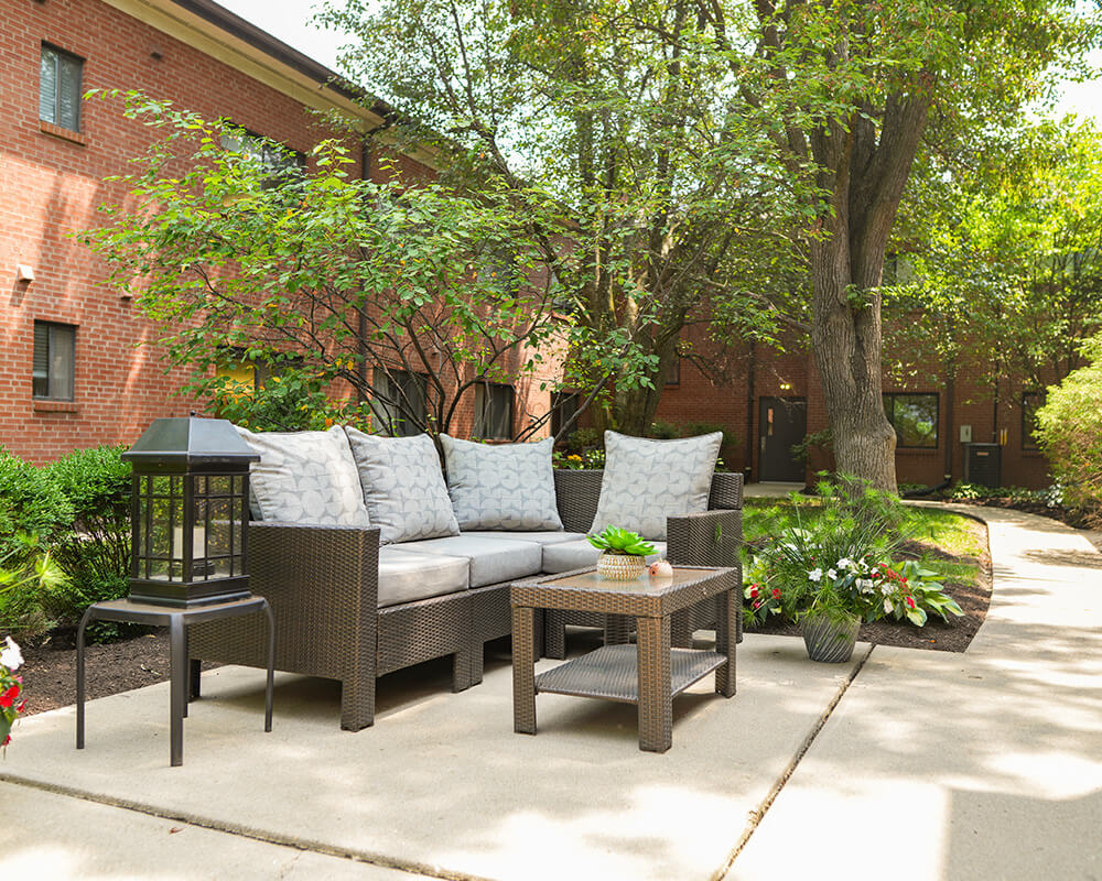 Outdoor seating area with wicker furniture and plants in a residential courtyard.