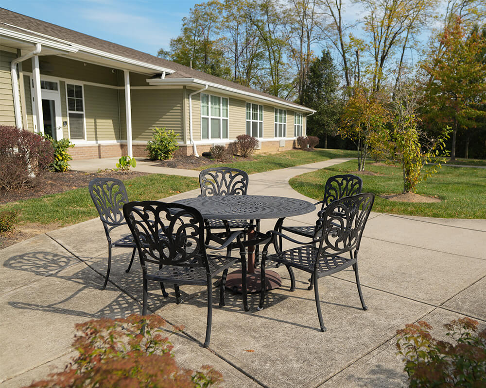 Outdoor seating with metal table and chairs in senior living community courtyard.