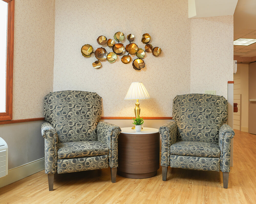 Cozy corner with two patterned chairs around a small table and lamp.
