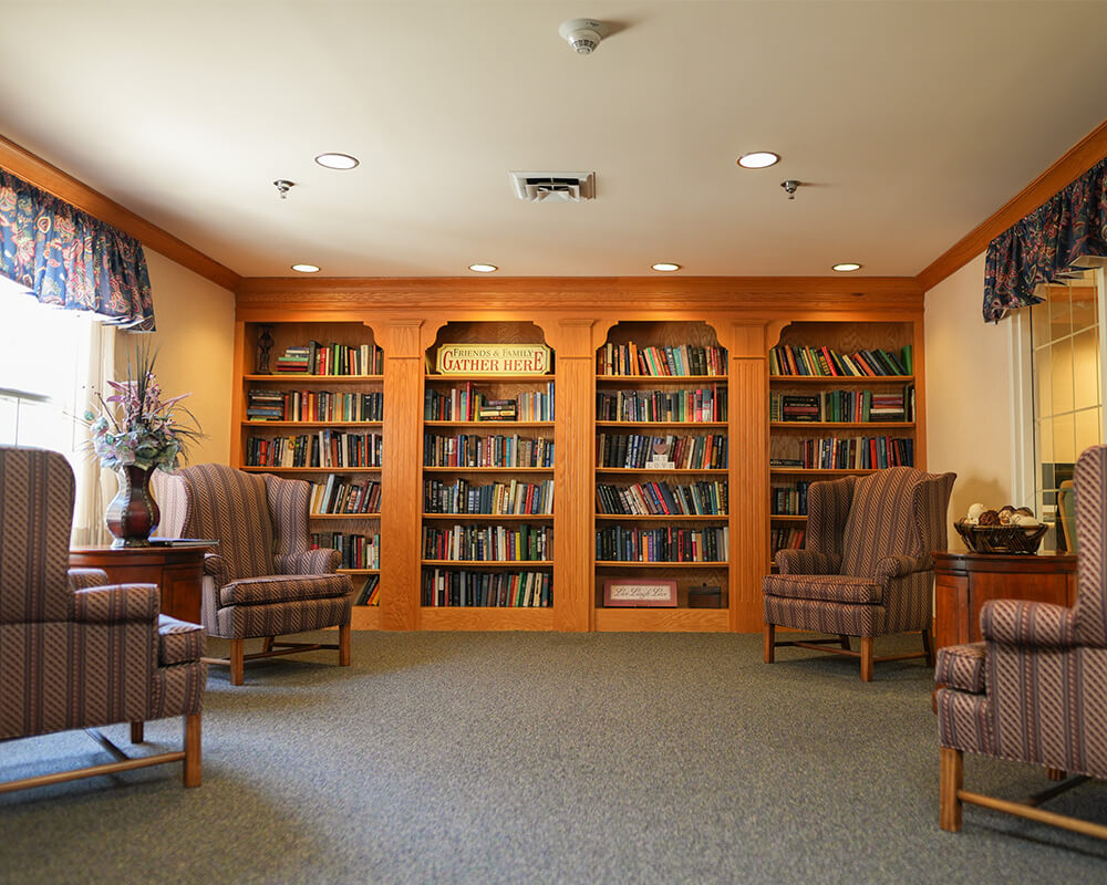 Cozy library with wooden bookshelves and comfortable armchairs in a common area.
