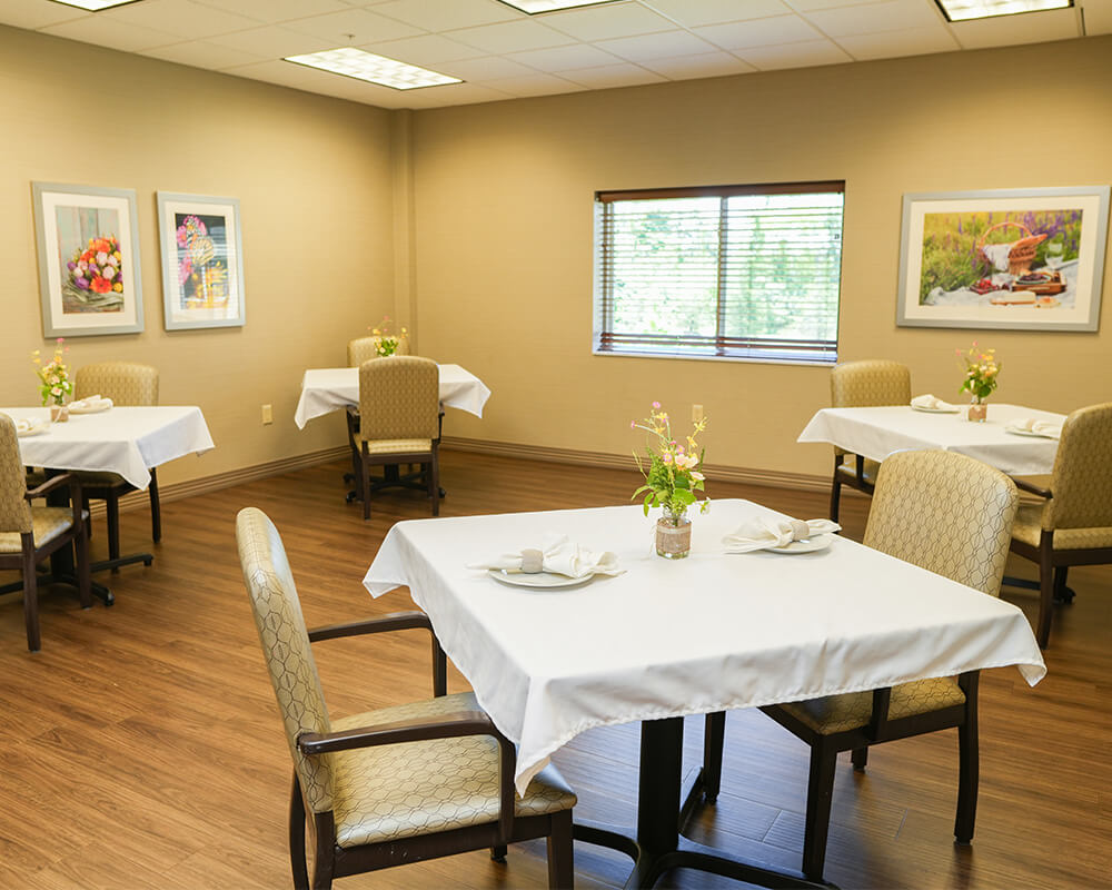 Bright dining room in a community center with tables set for meals.