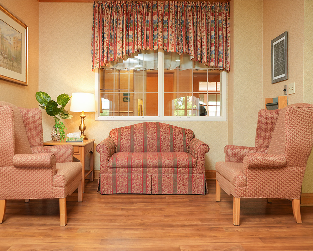 Cozy seating area with patterned sofa and chairs, lamp, and potted plant.