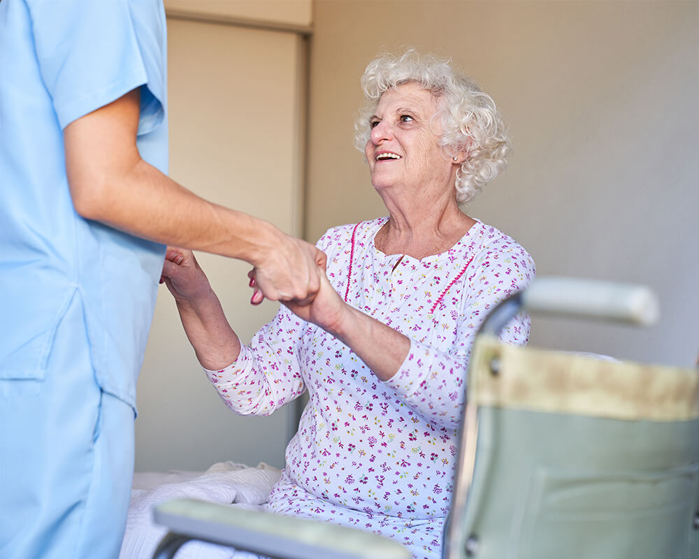 Smiling elderly woman holding hands with caregiver in a comfortable unit.