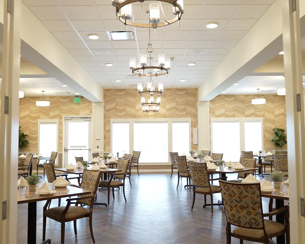 Elegant dining room with set tables in a senior community building.
