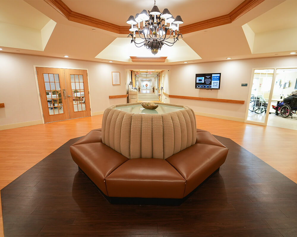 Spacious hallway with a chandelier and modern seating in a living community.