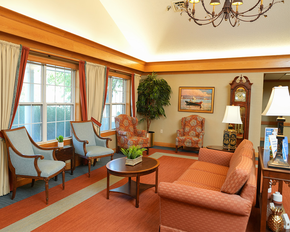 Elegant lounge area with armchairs, sofa, and chandelier in a senior living community.