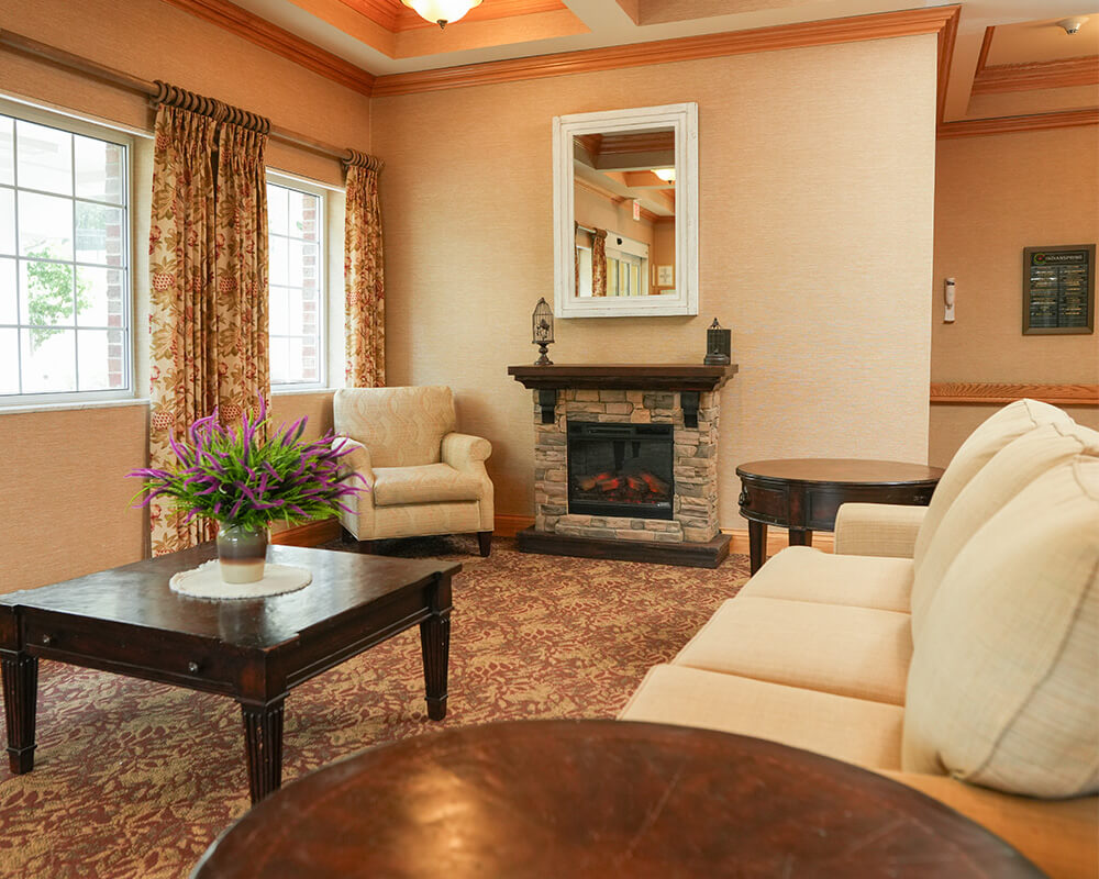 Cozy lounge with fireplace, armchair, and elegant decor in a senior living community.