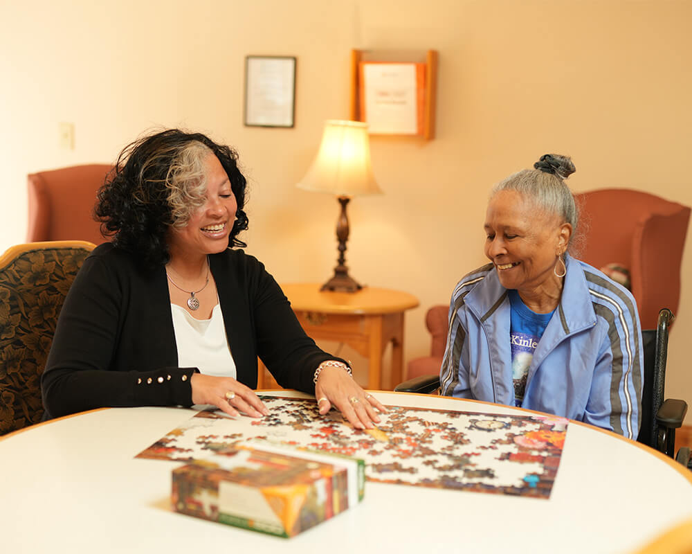 Two women enjoying a puzzle together in a cozy living area.