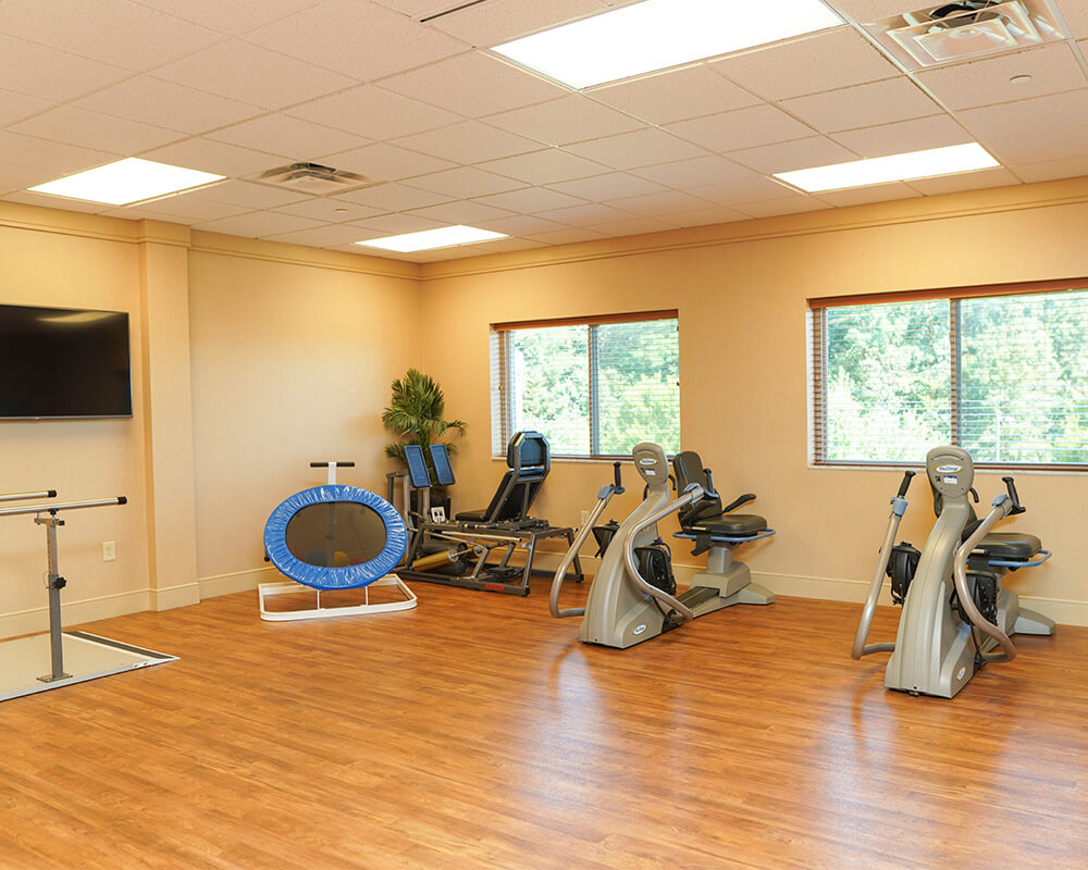 Spacious exercise room with various fitness equipment and wooden flooring.