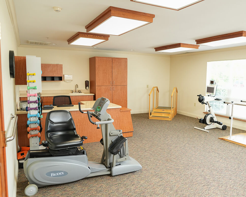Exercise room with stationary bikes and chairs in a senior living community.