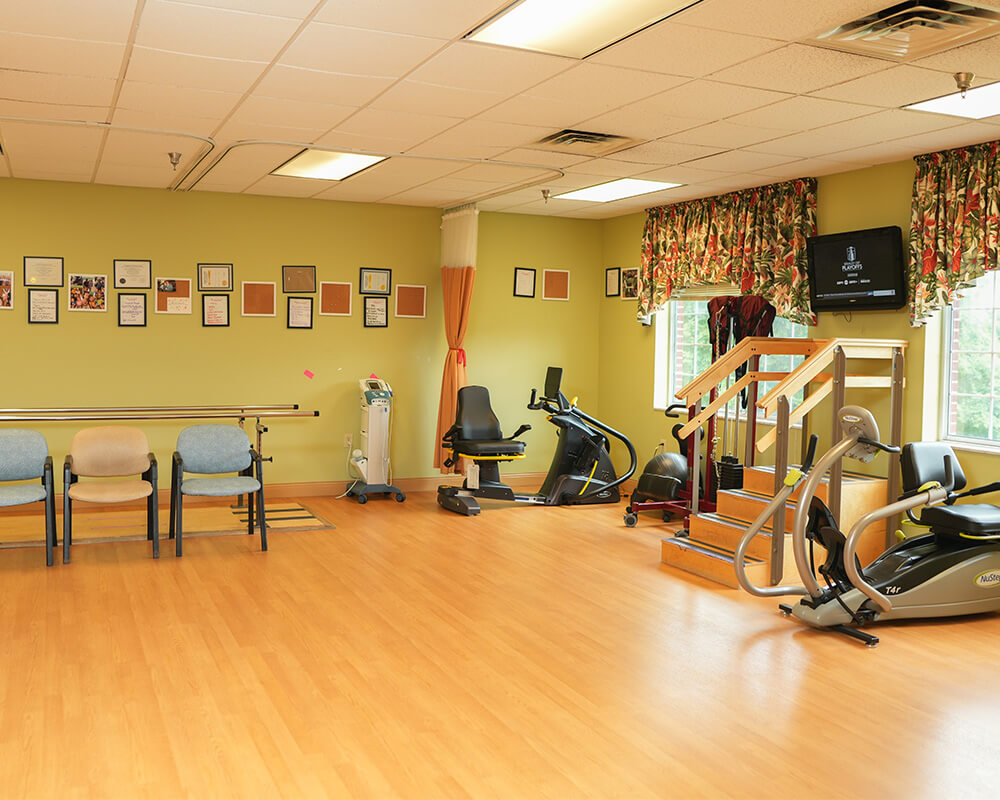 Exercise room with equipment and chairs in a senior living community.