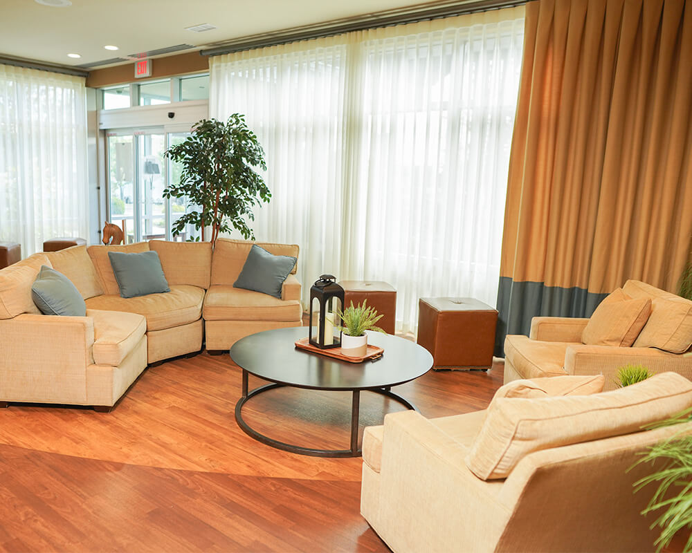 Cozy seating area with beige couches and a round table in a bright communal space.