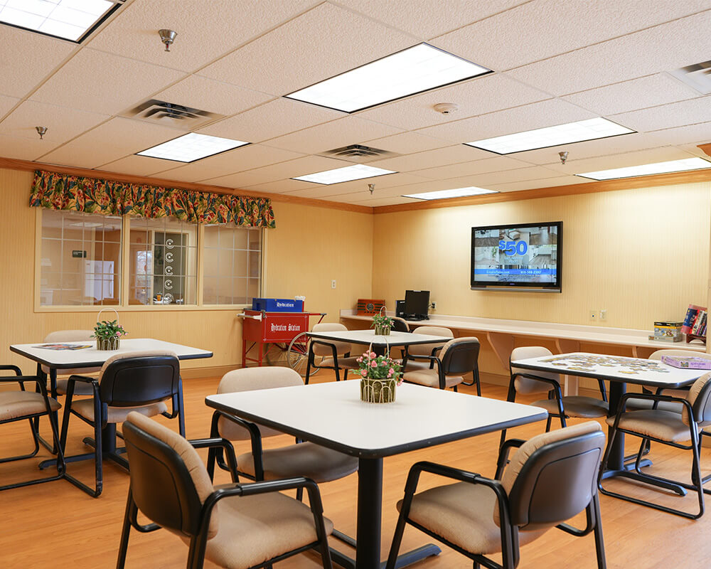 Community room with tables, chairs, and a puzzle on a table in the foreground.