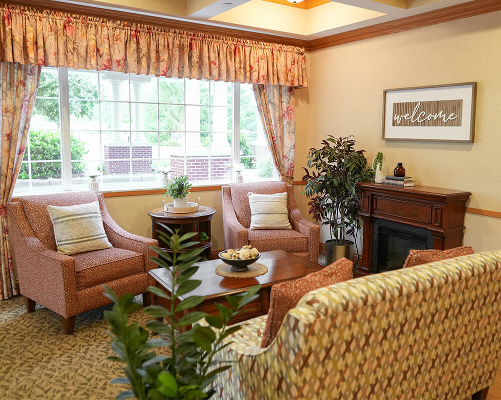Cozy living area with armchairs, welcoming decor, and large window overlooking garden.